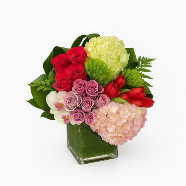 Opulent Bloom with hydrangeas, orchids, roses and tulips in a clear glass vase