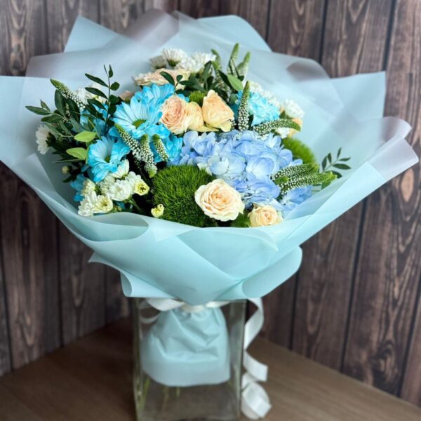 Blue Tenderness bouquet with blue hydrangea and delicate spray roses in a glass vase