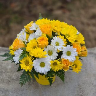 A bouquet in a bright mug with yellow roses and white and yellow chrysanthemums
