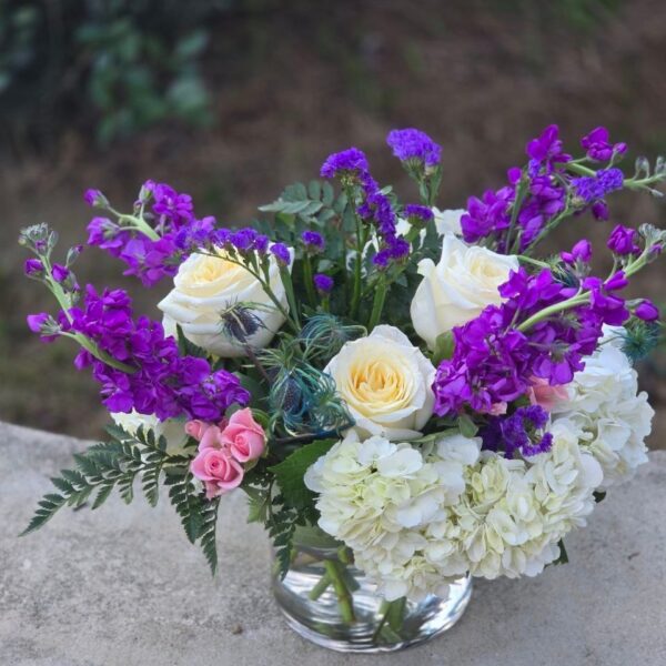 White and purple flower bouquet with hydrangea, matthiola, roses and spray roses in a glass vase