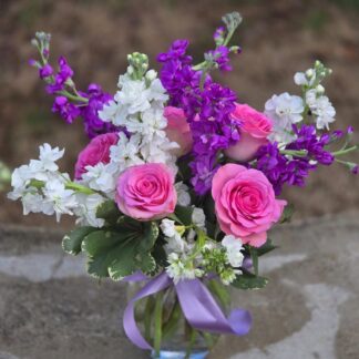 A bouquet in a glass vase with a pink rose and matthiola