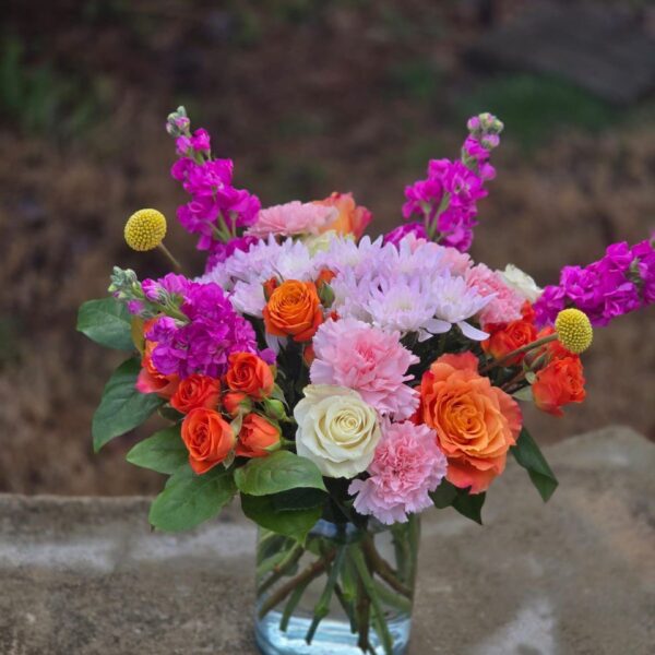 Warm autumn flower bouquet with seasonal blooms and rich colors arranged in a glass vase
