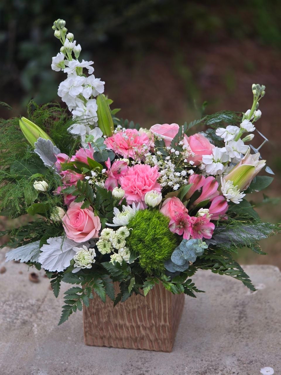 A bouquet in a glass vase with a pink rose, white matthiola, pink alstroemeria, and lily