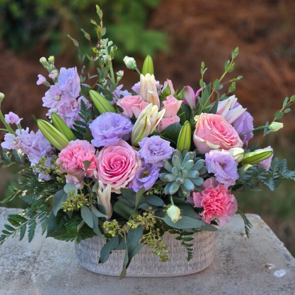 Pink flower basket with pink lilies, roses, carnations, spray roses, matthiola and purple eustoma in a wicker basket