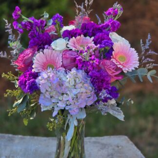 A bouquet in a glass vase with hydrangea, purple matthiola, pink gerbera, pink and white rose, statice and purple carnation