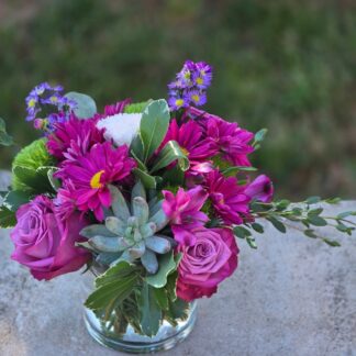 A bouquet in a glass vase with purple roses, Monte Cosino, lilac spray chrysanthemum, mixed grasses and dianthus – a mysterious luxury for special moments