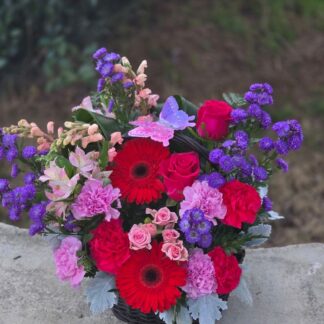 A bouquet in a wicker basket with gerberas, roses, carnations, alstroemeria, and Monte Casino