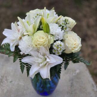 Bouquet in a glass vase with white lily, white carnation, fern and daisy