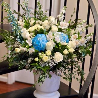 Bouquet in a plastic vase with white roses, blue hydrangea, spray roses, alstroemeria, gypsophila, matthiola and mixed grass