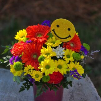 A bouquet in a colored glass vase with yellow chrysanthemum and gerbera