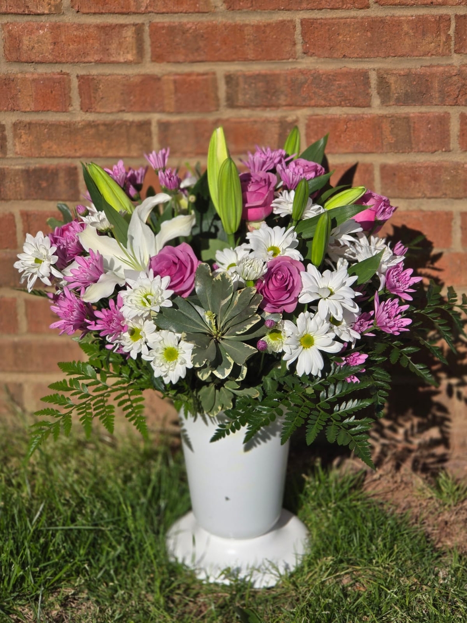 Business bouquet in a plastic vase with a white lily, a pink rose, and white and pink spray chrysanthemum