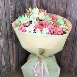 A bouquet in stylish packaging with a peony rose, a spray pink rose, and a spray chrysanthemum