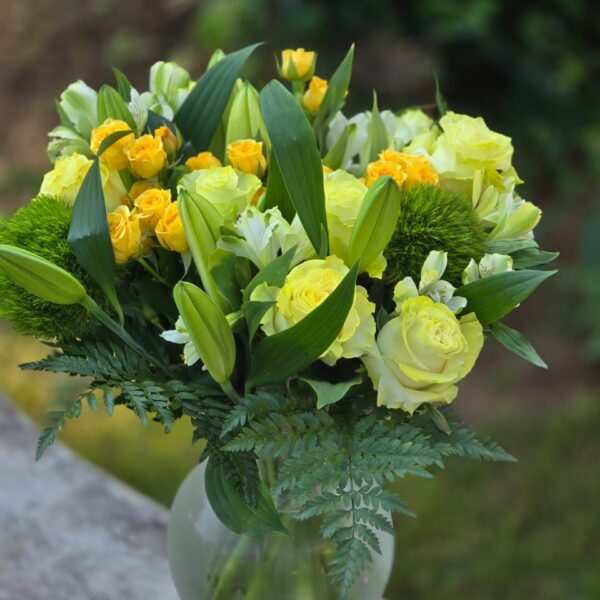 Golden Harmony yellow roses with white lilies, alstroemeria and green dianthus in a glass vase