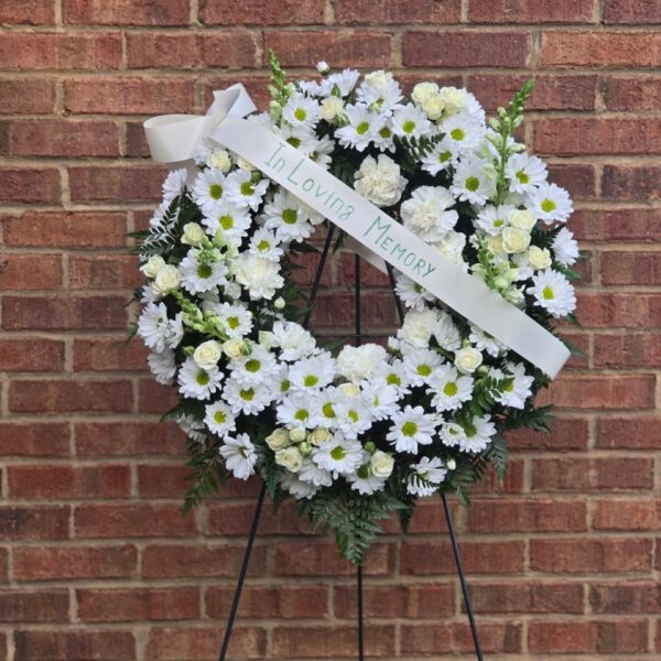 White Tribute funeral standing spray with white chrysanthemums, spray roses, carnations, stock, and fern